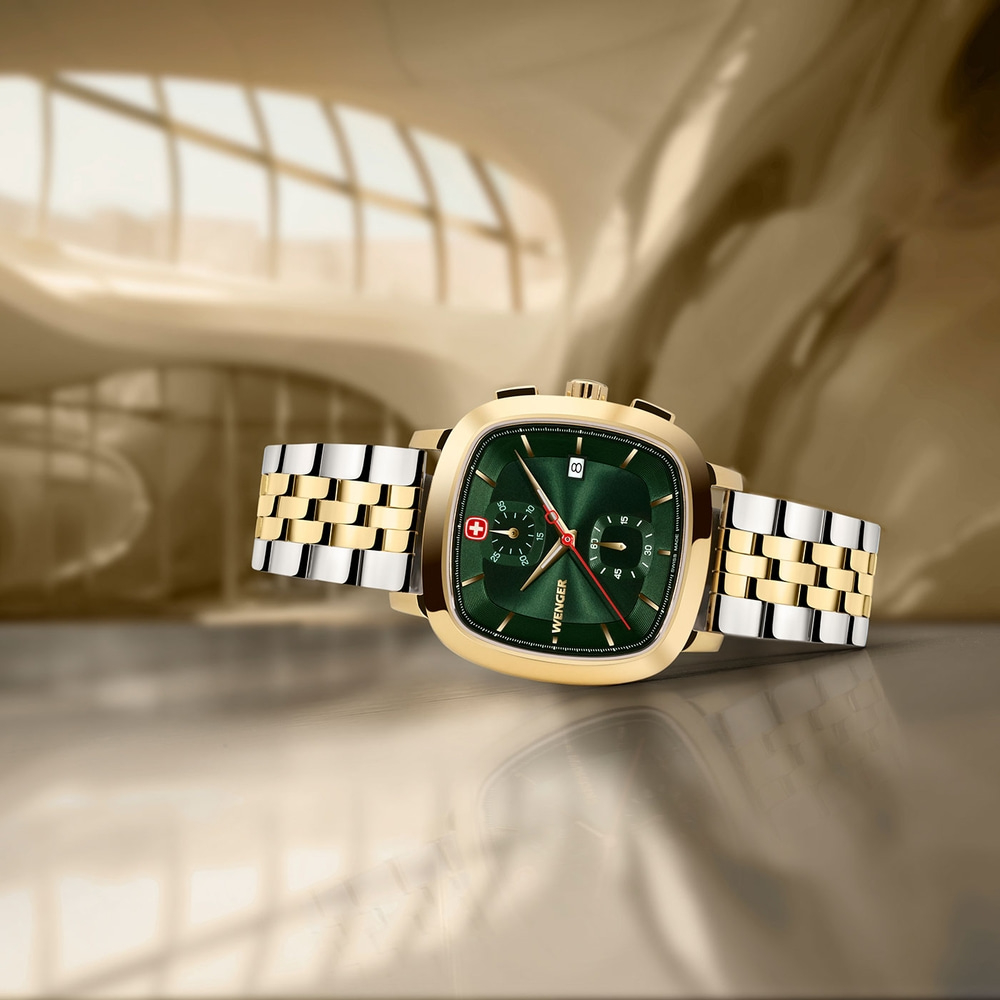 Close-up of a gold watch with a green face and a gold and silver band.