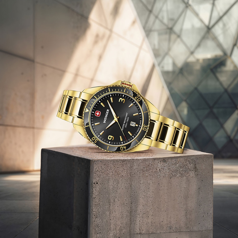 Gold Wenger watch on concrete block with blurred background, Swiss made, water resistant.