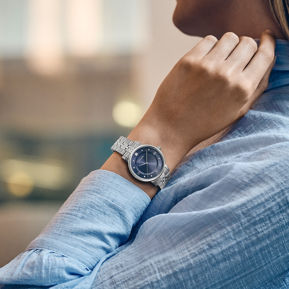 A woman in a blue shirt wearing a silver watch on her wrist.