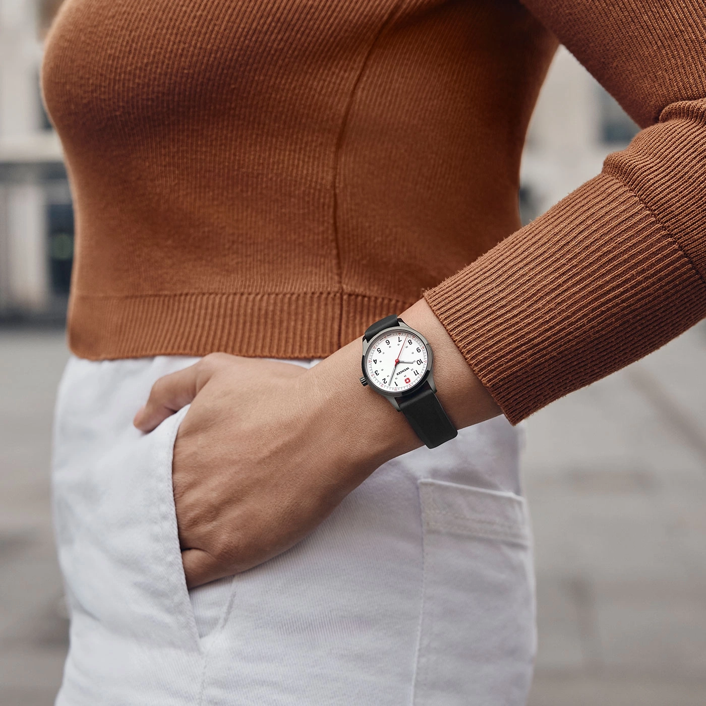 Person trägt eine Uhr mit schwarzem Armband und weißem Zifferblatt.