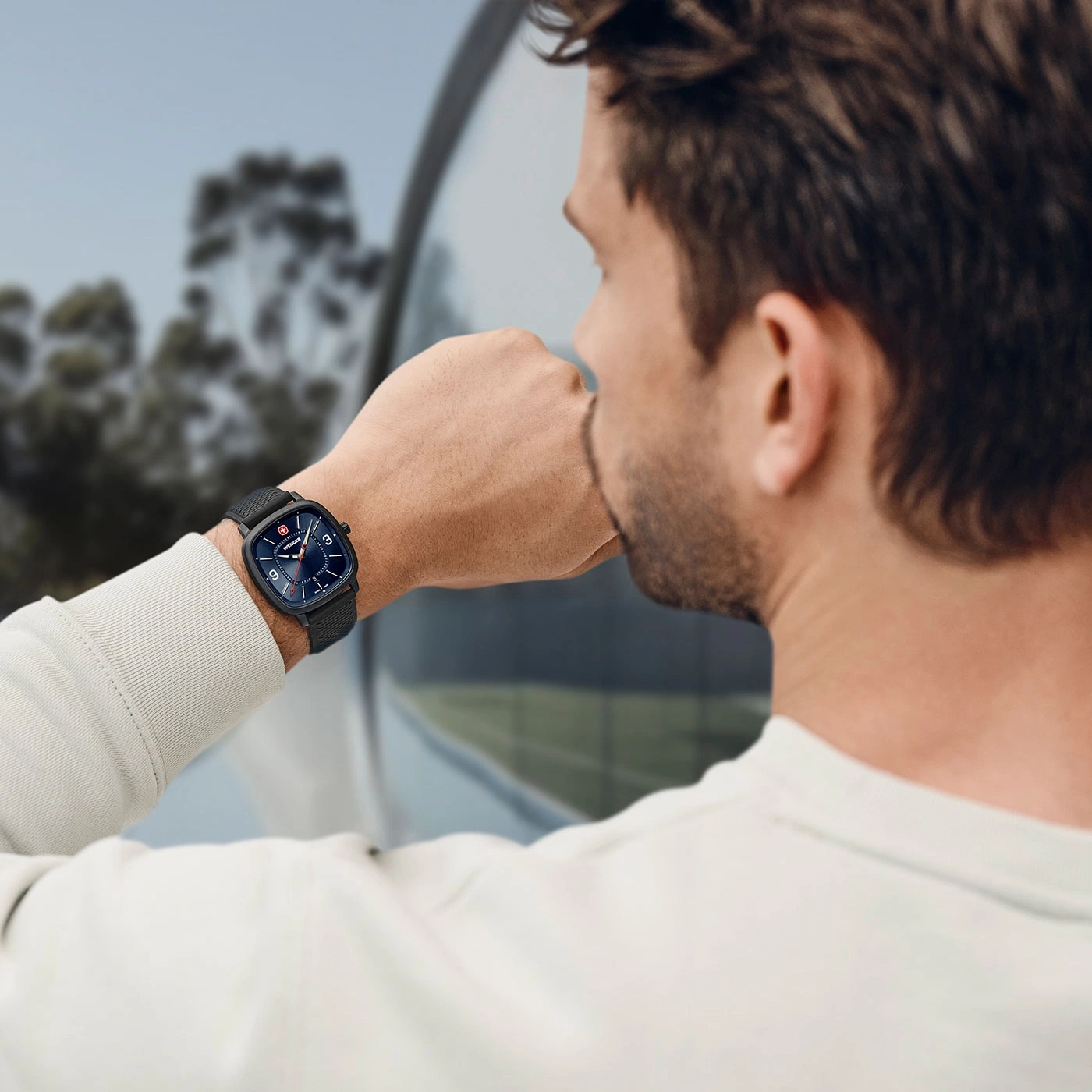 Man wearing watch looking out window, close-up shot of the watch