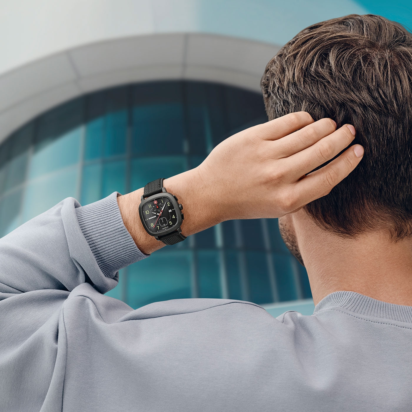 Man scratching head wearing watch in front of a building