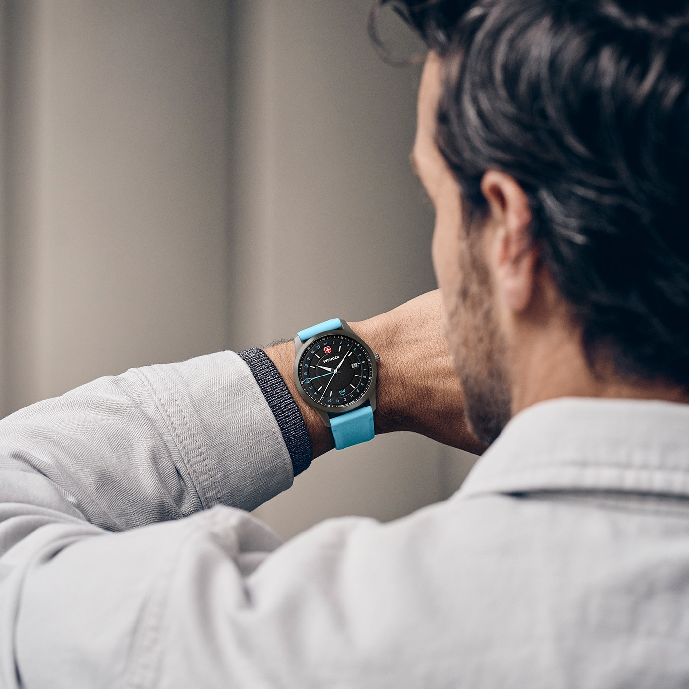 Man wearing a watch with a blue strap on his wrist.