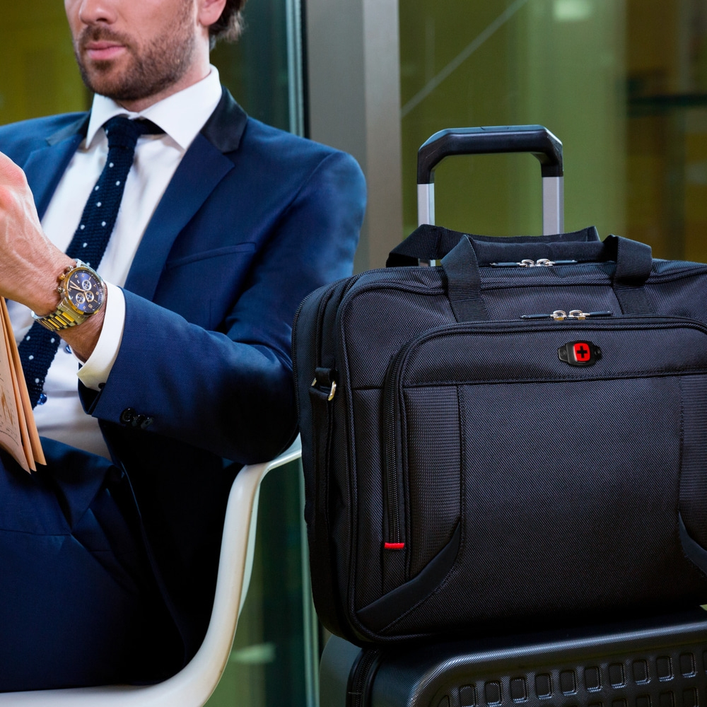 Man in suit with watch and luggage, waiting at the airport.