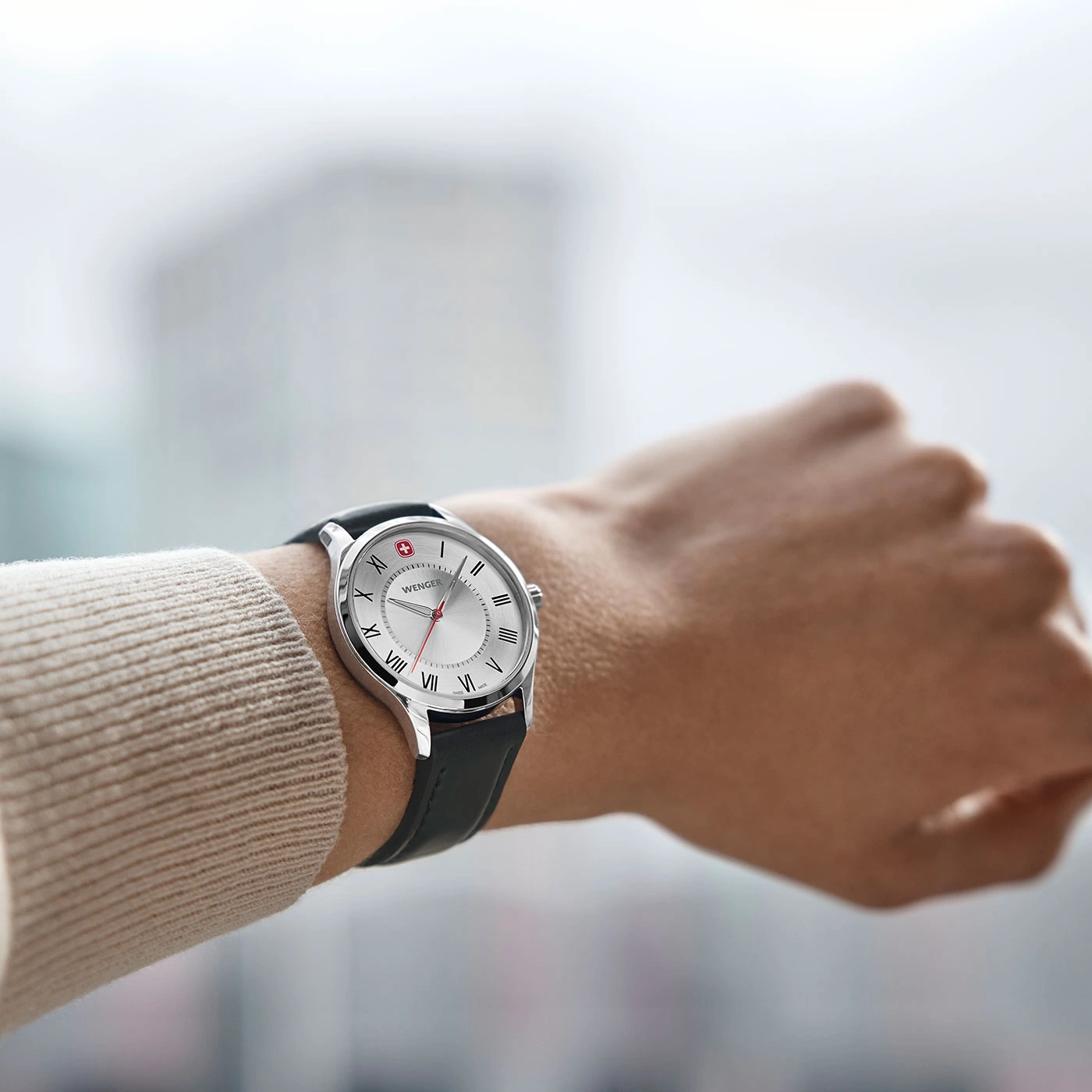 Wristwatch with silver face, black leather strap, Wenger brand, on a wrist