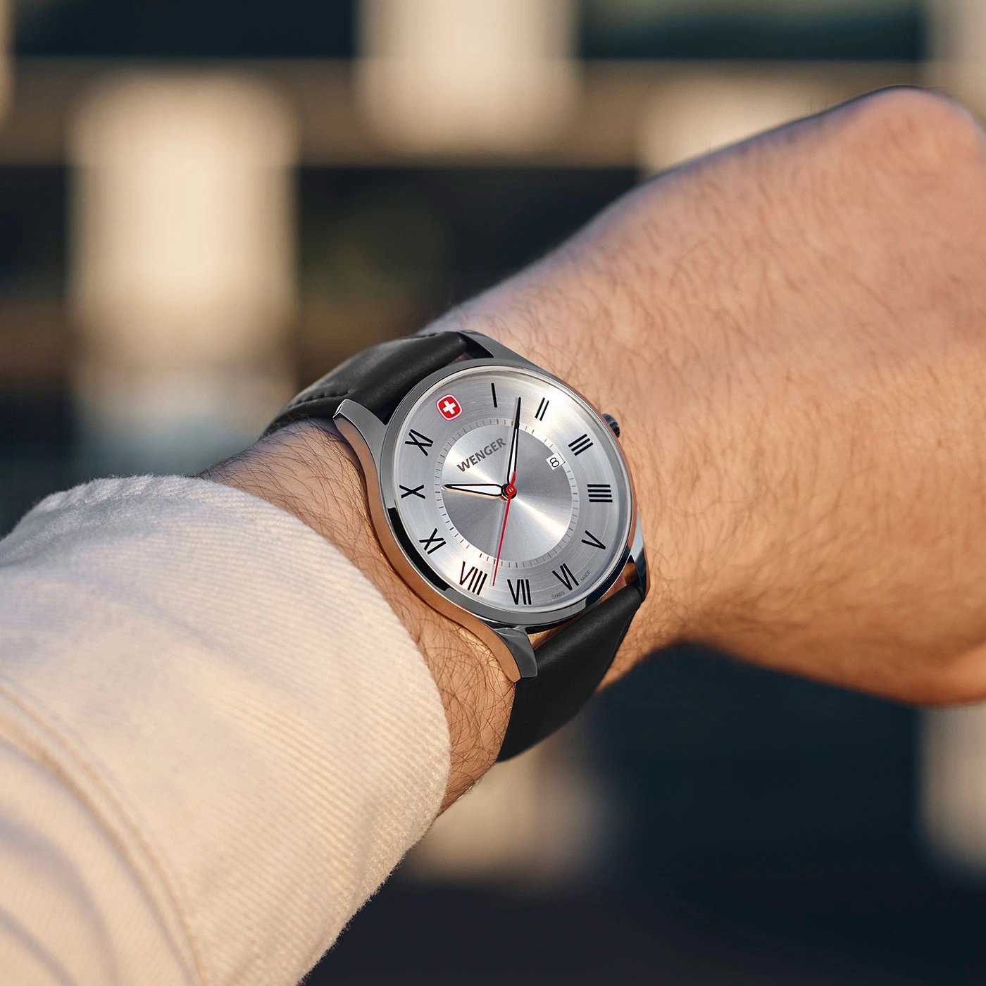 Wenger watch on wrist, silver dial, black leather strap, Swiss flag, close-up shot