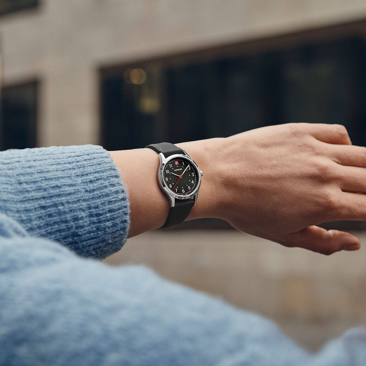 Watch on wrist, black dial, silver case, black strap, person wearing watch, close-up shot
