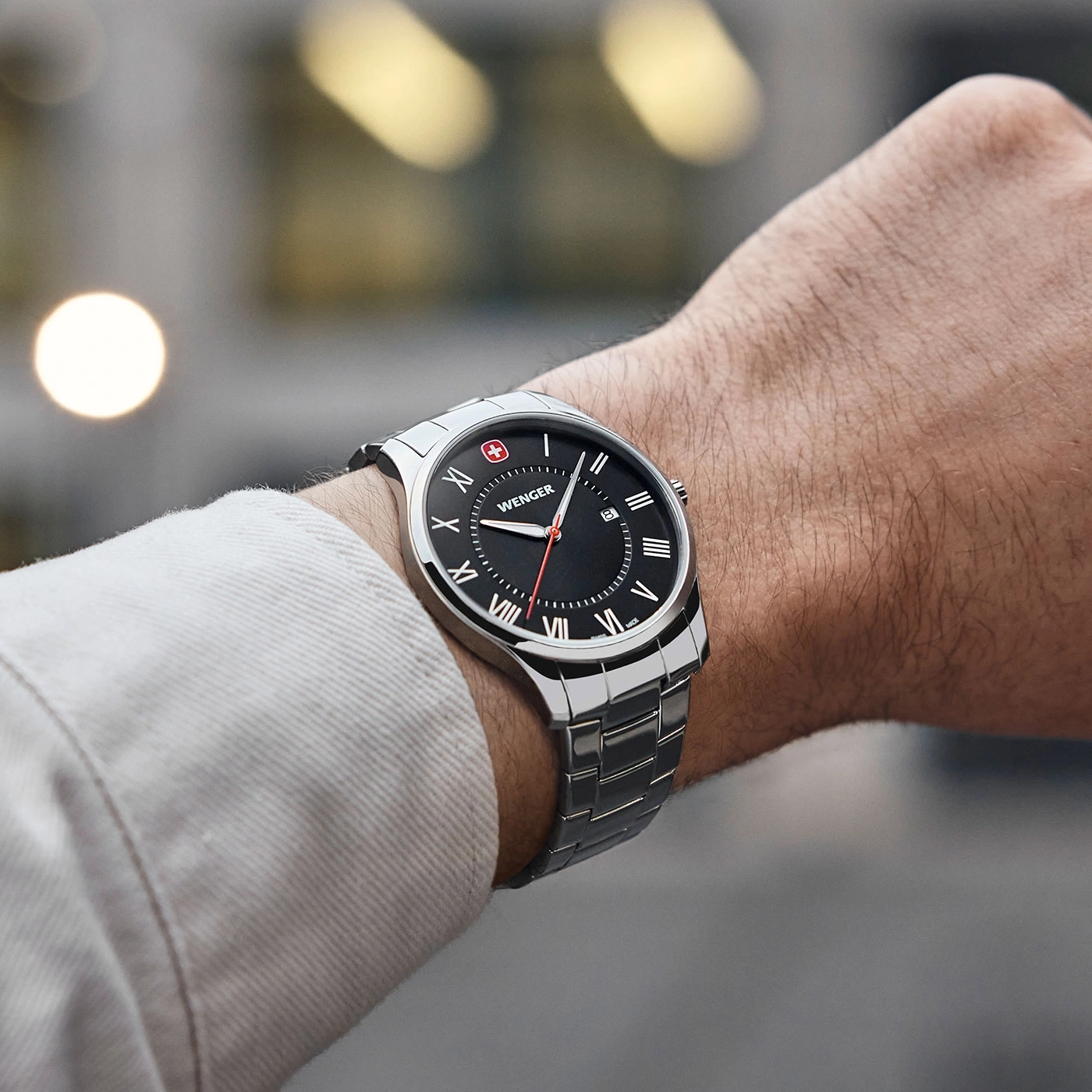 Wristwatch with black face, Roman numerals, and a silver band on a wrist