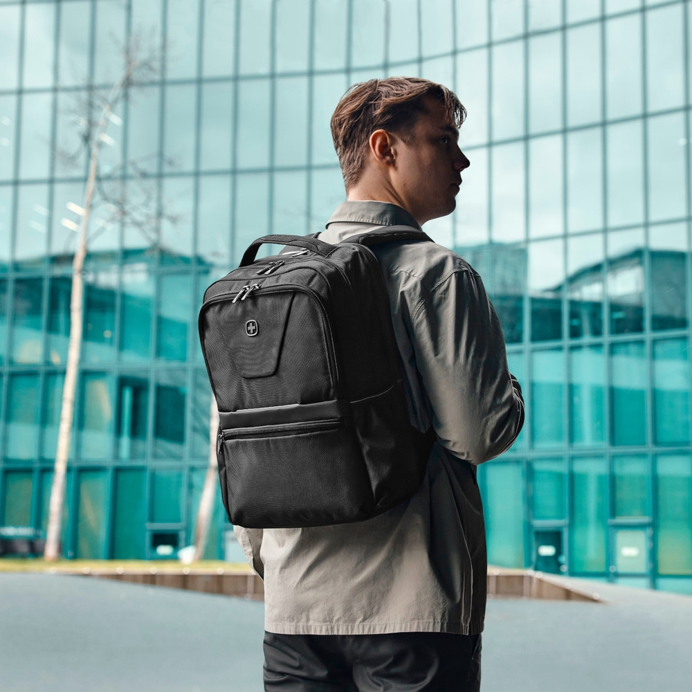Man with black backpack in front of a modern building