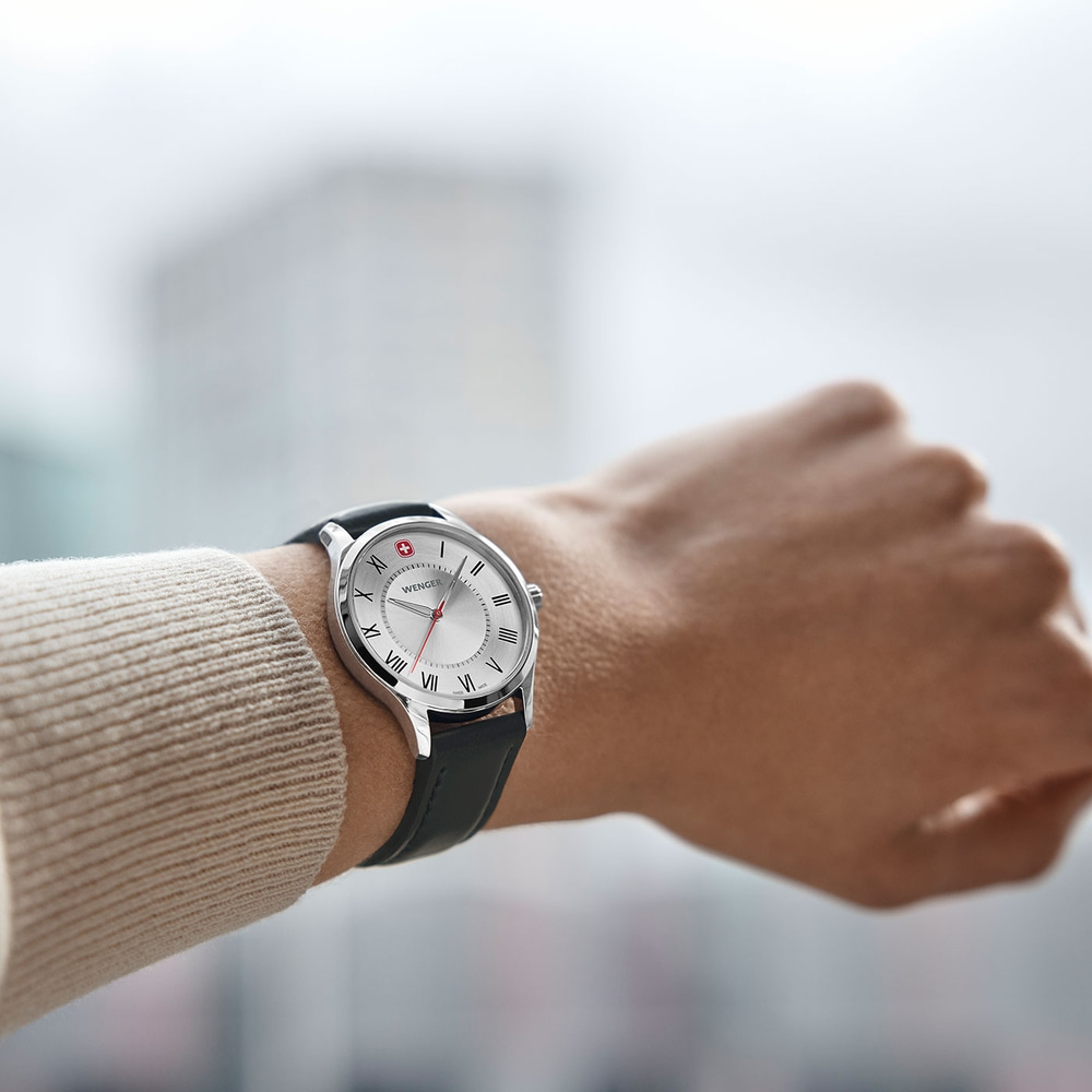 Wristwatch with silver face, black leather strap, Wenger brand, on a wrist