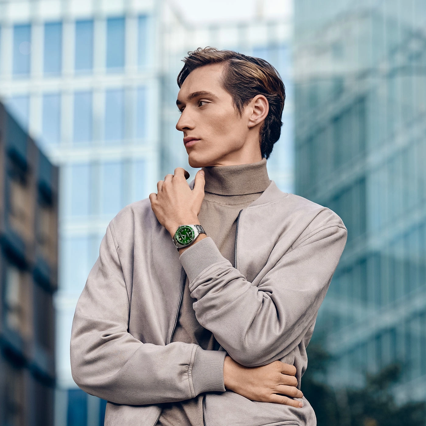 A man in a jacket with a watch in front of a building.