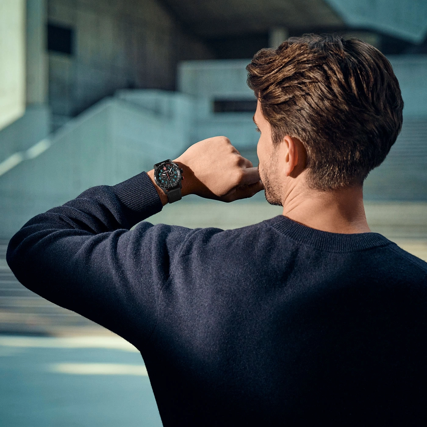Man looking at his watch, with a building in the background, checking time