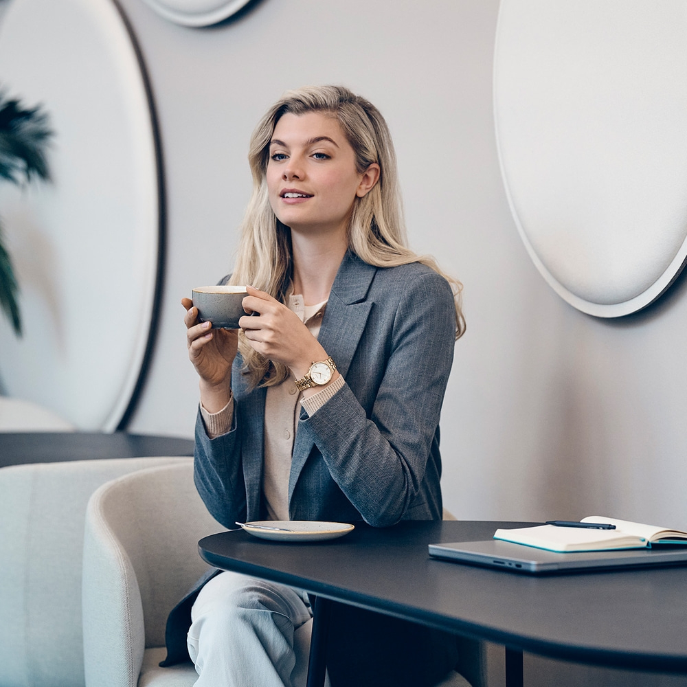 A woman with blonde hair drinks coffee in a modern cafe.