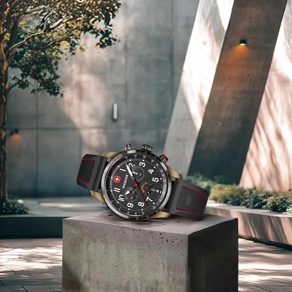 Wenger watch on concrete block, black dial, red accent, modern design, outdoor scene, Swiss made.