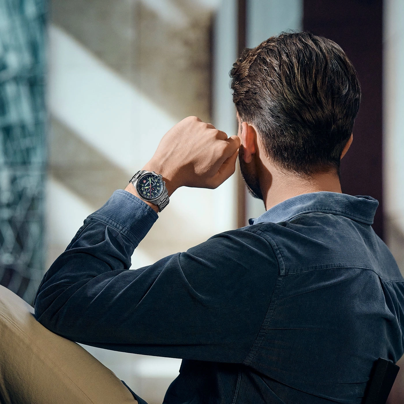 Mann mit Uhr, der nachdenklich in die Ferne blickt, in einem dunklen Hemd.