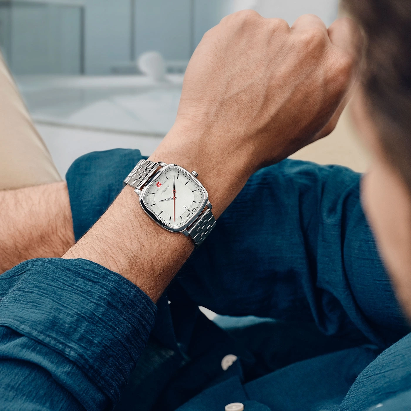Man wearing a silver watch with a white face and red accent on his wrist