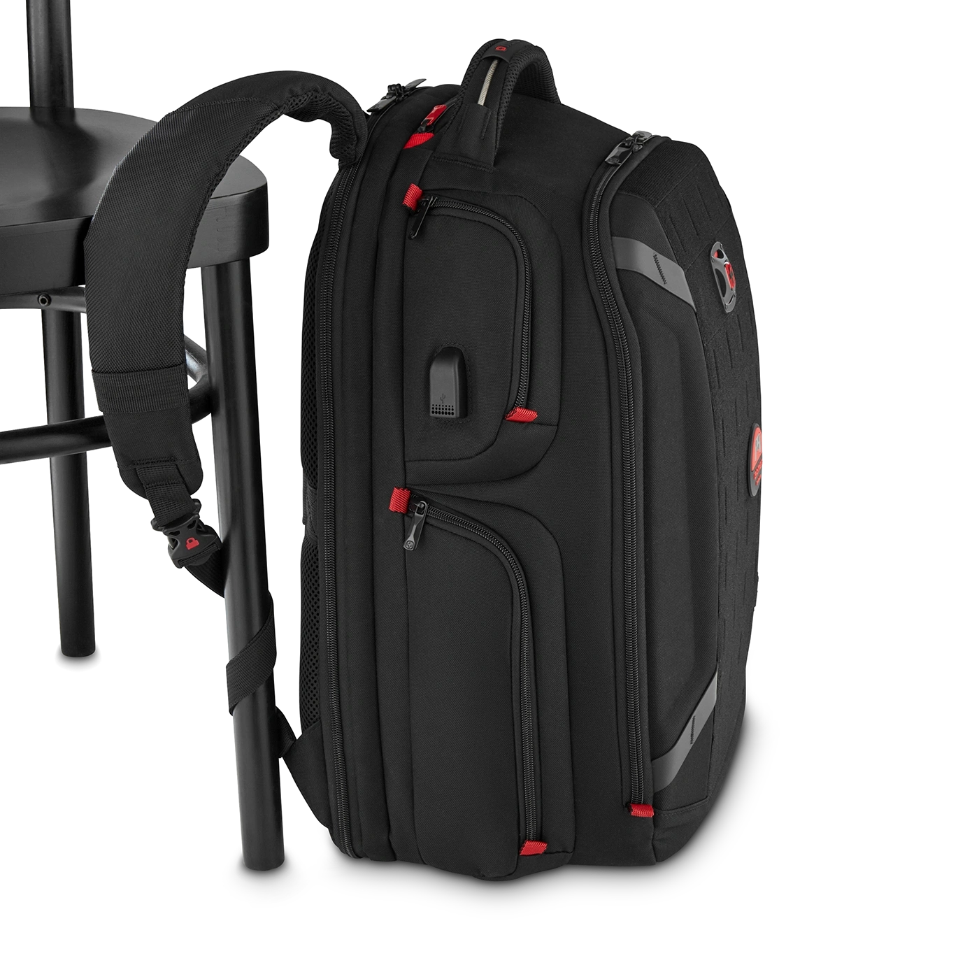 Black backpack with red accents leaning against a chair, close-up shot