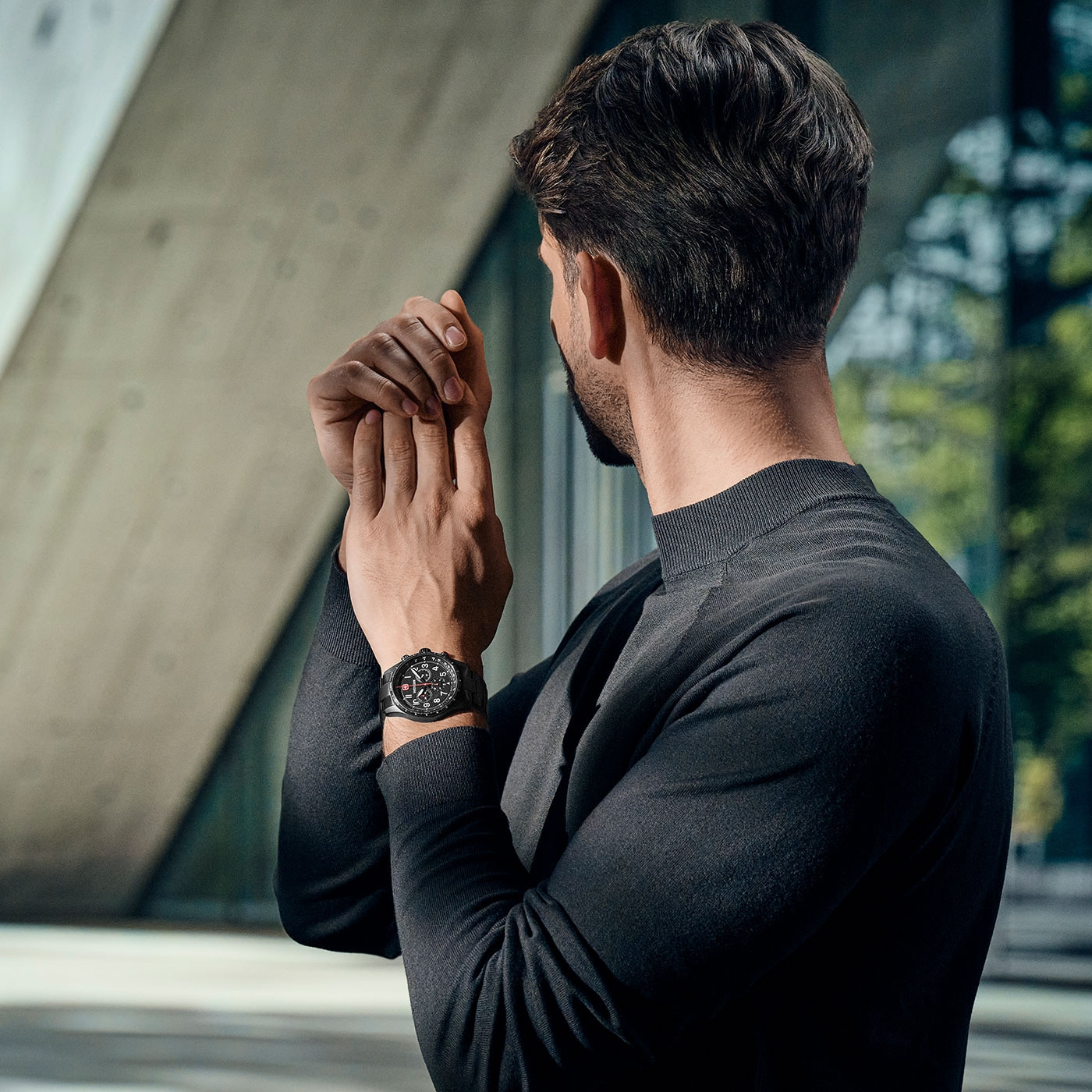 Man with watch looking at his hand, in front of a modern background