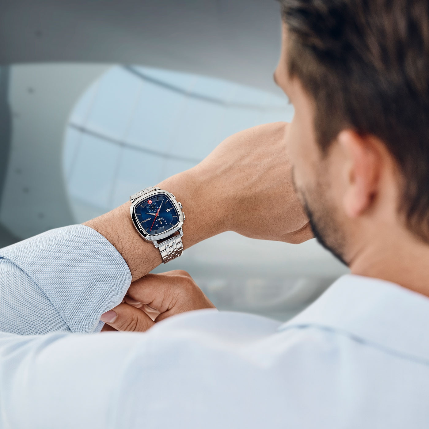 Man looking at his watch. Wristwatch with blue dial and silver bracelet. Close-up shot.