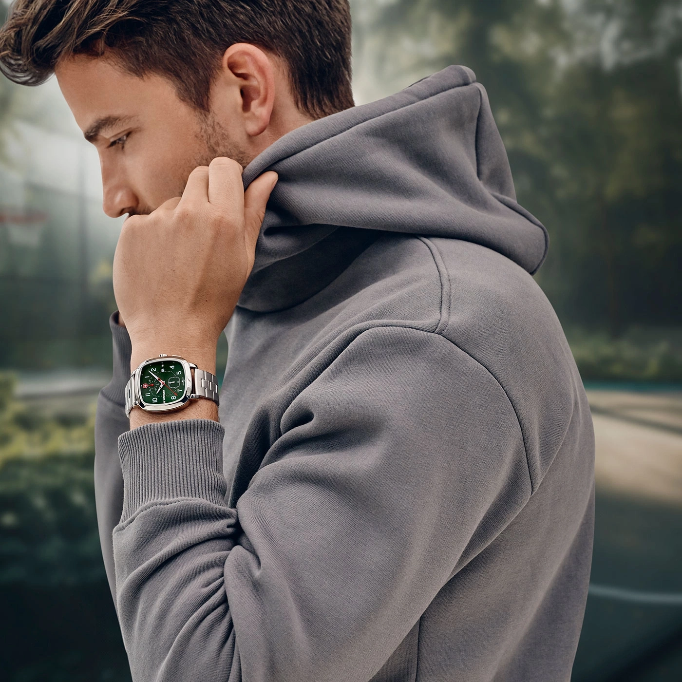 Mann mit Uhr und Kapuzenpullover, der sich die Kapuze hochzieht.