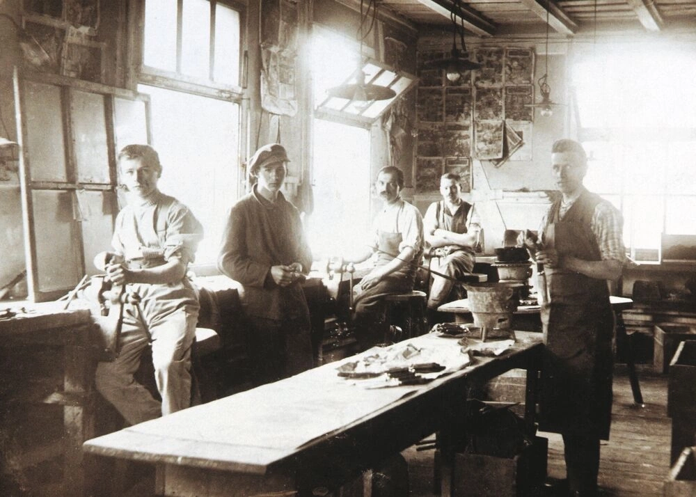 Five men in a workshop working on tools.