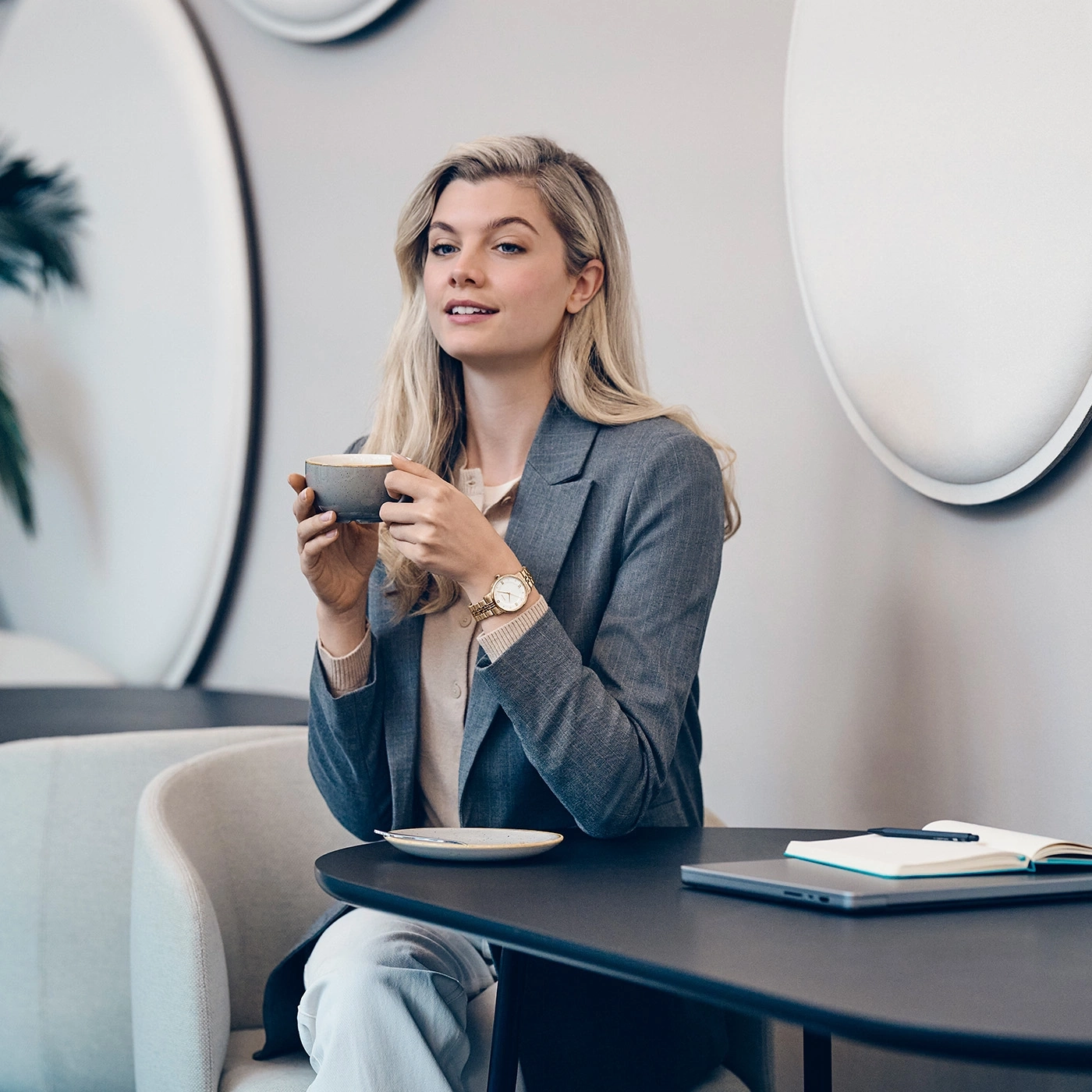Eine Frau mit blonden Haaren trinkt Kaffee in einem modernen Café.