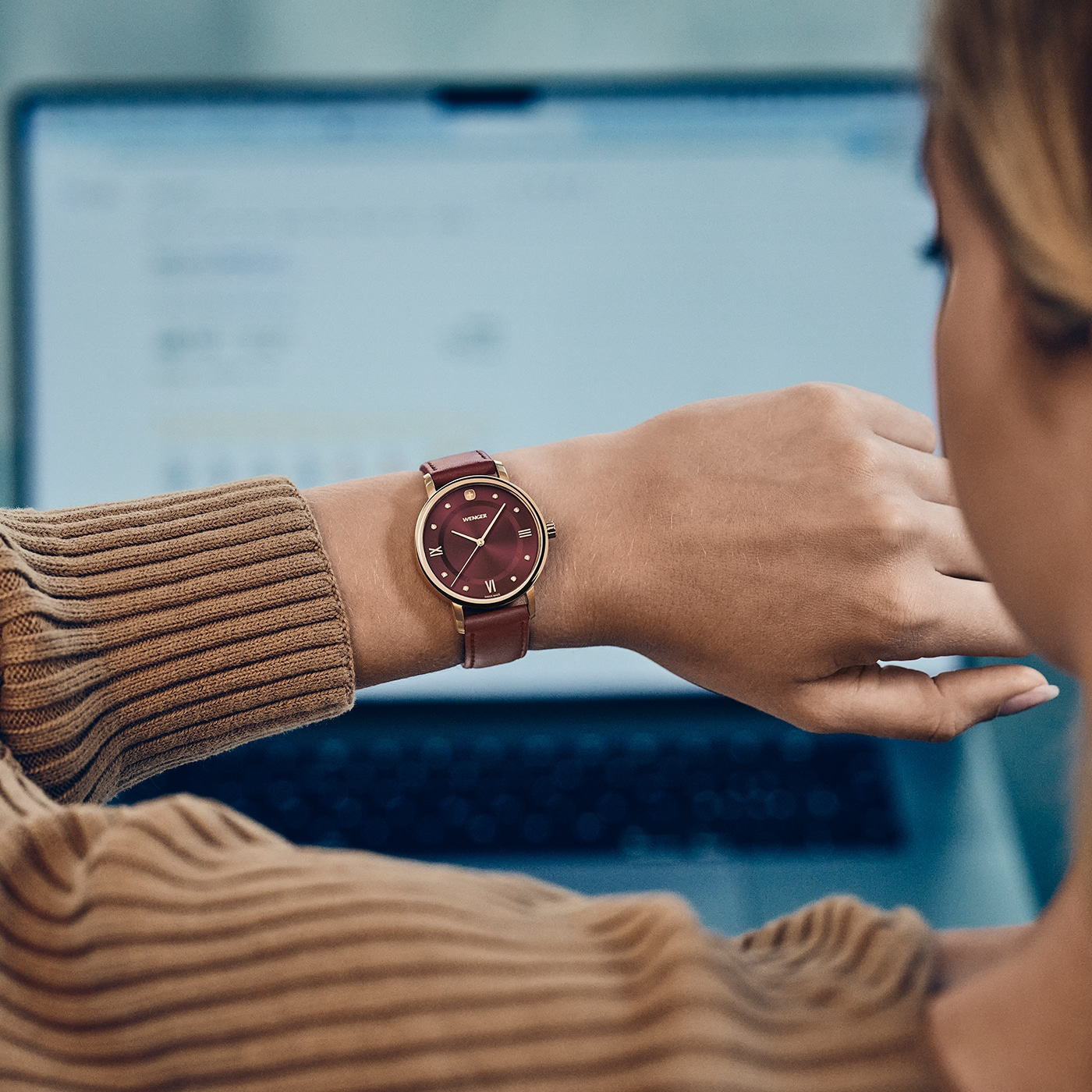 A woman wears a watch while working on a laptop.