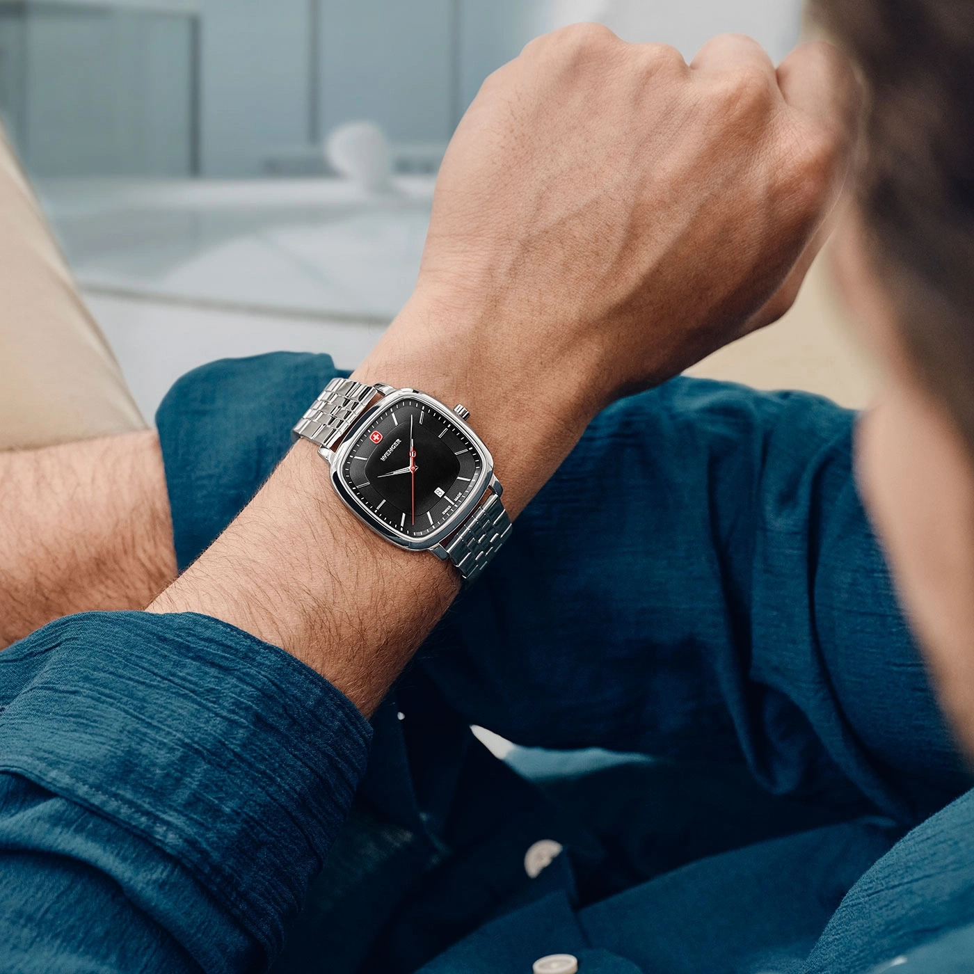Watch on wrist, man in blue shirt, close-up, square dial, silver bracelet