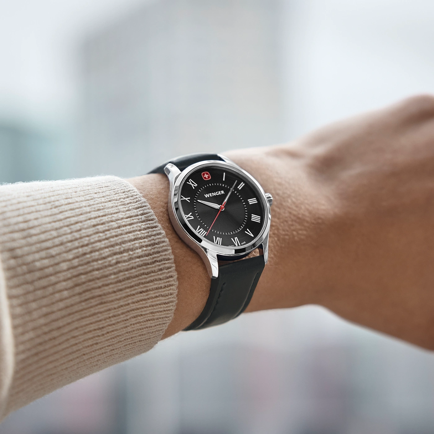 Wenger watch on wrist, black dial, leather strap, Roman numerals, close-up shot