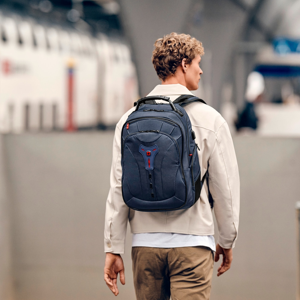 Man with backpack walking in the city, seen from behind, urban scene