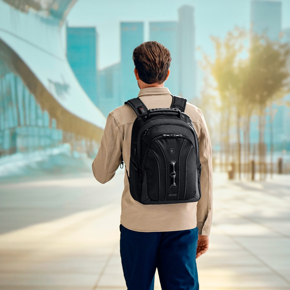 Man with black backpack walking in a city, seen from the back, urban scene