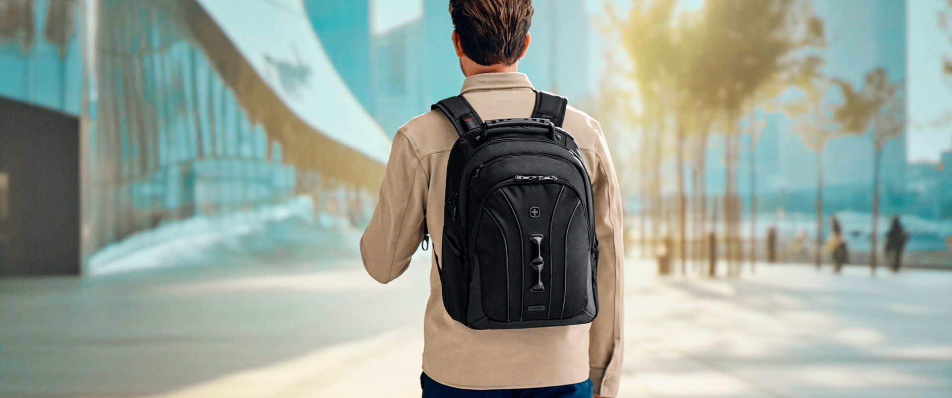 Man with black backpack in front of blurred background in the city