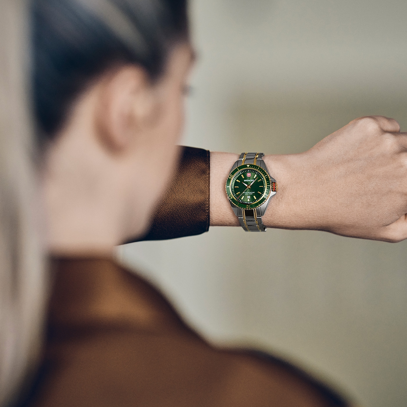 A man wears a green Wenger wristwatch on his wrist.