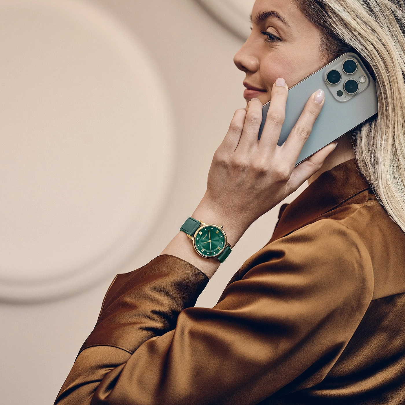 Eine Frau telefoniert mit einem Smartphone und trägt eine grüne Armbanduhr.