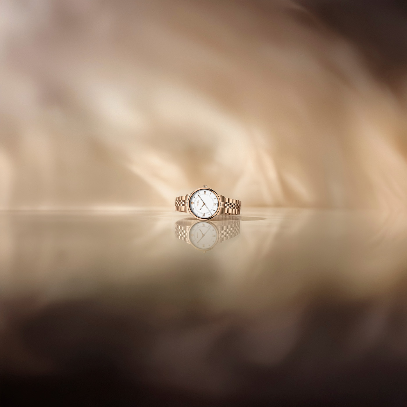 A gold watch with a white face rests on a reflective surface.