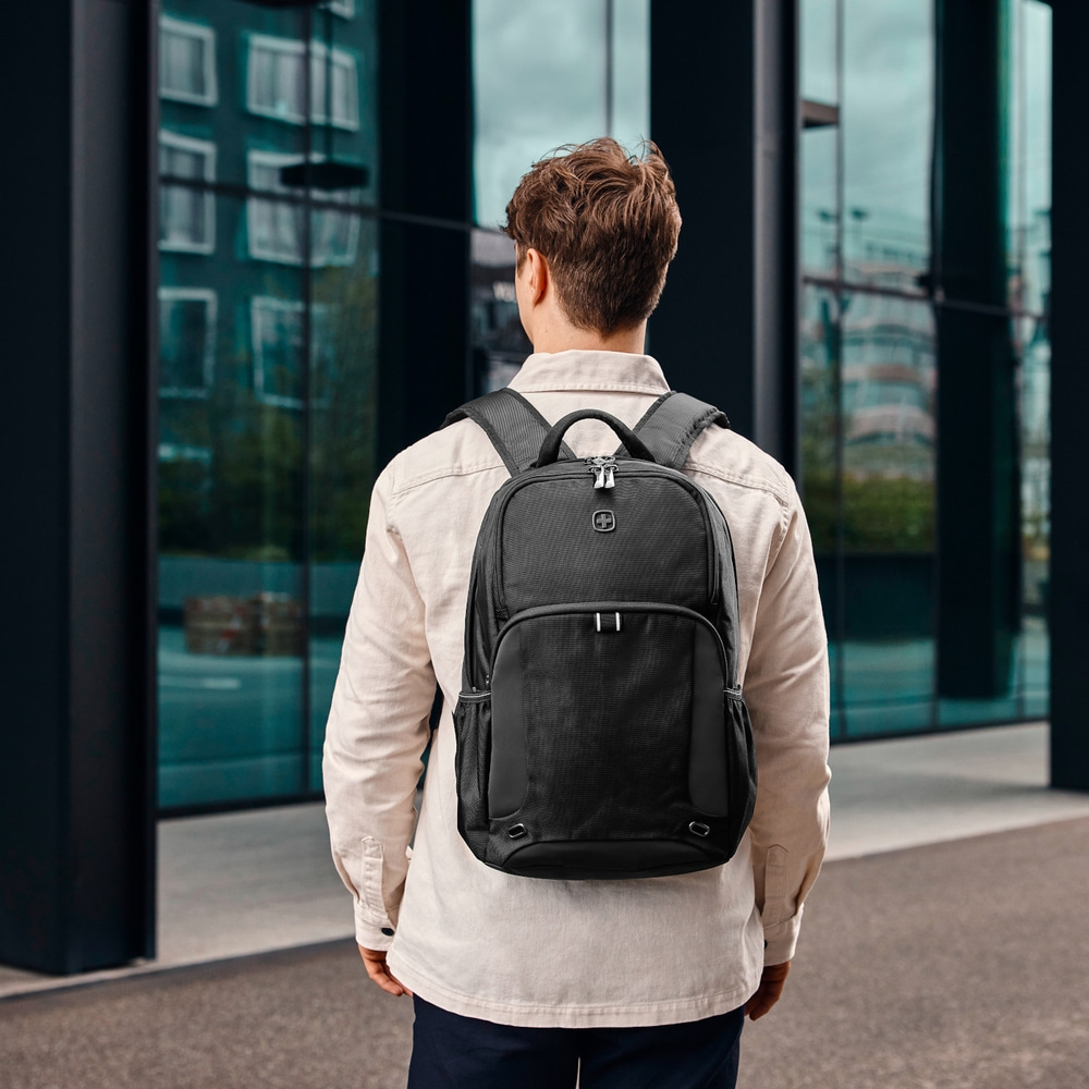 Man with black backpack in front of a modern building