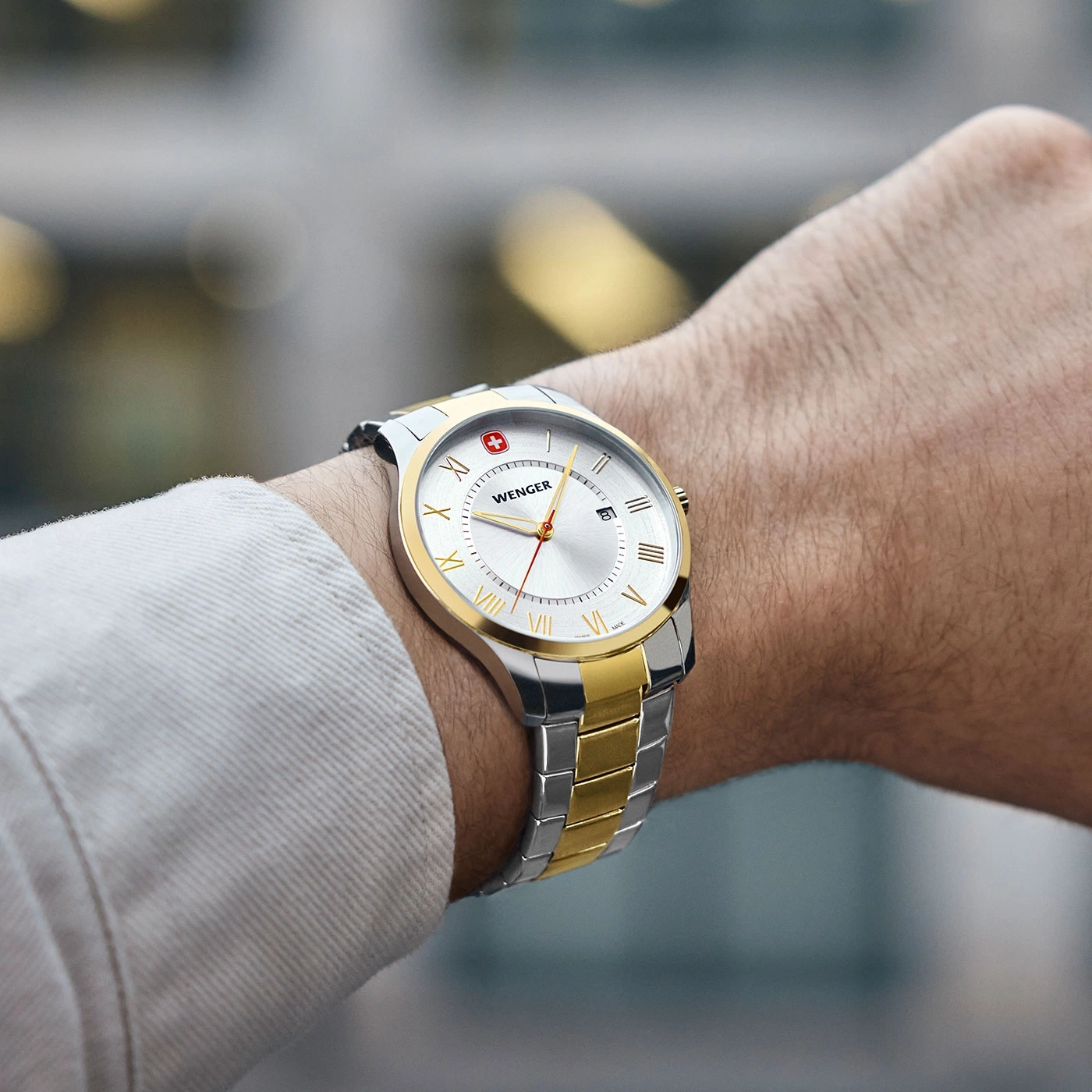Wenger watch on wrist, silver and gold band, white dial, Roman numerals, Swiss cross