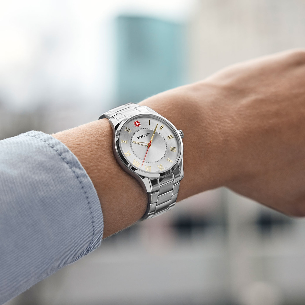 Wristwatch on wrist, silver band, light dial, Wenger brand, close-up shot