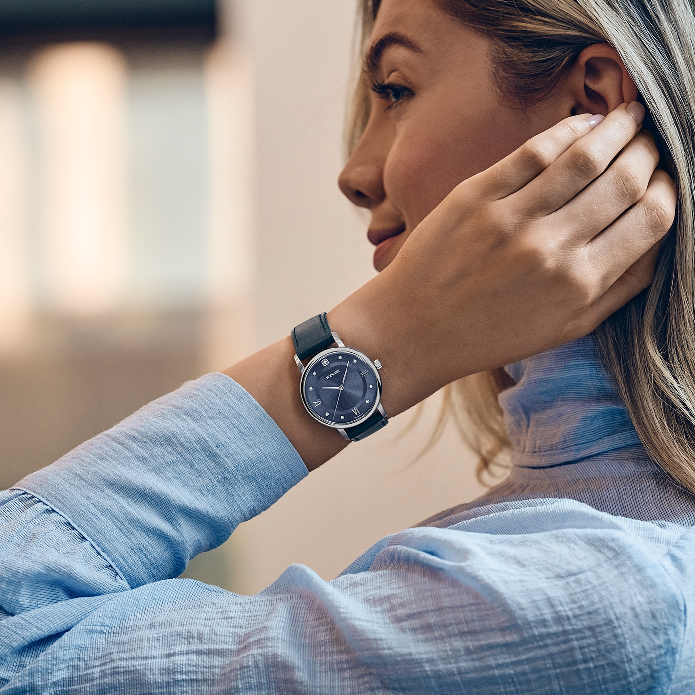 A woman wearing a watch on her wrist and a blue button-up shirt.