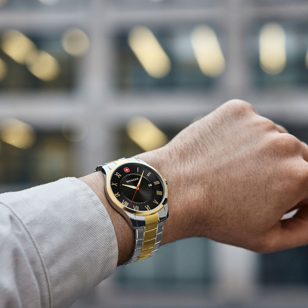 Watch on wrist, gold and silver, black dial, Wenger brand, close-up shot
