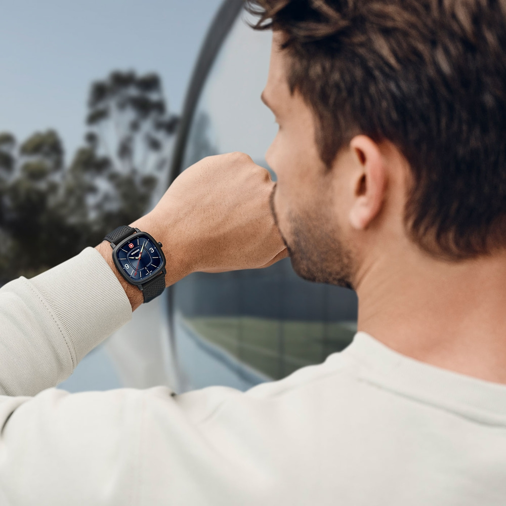 Man wearing watch looking out window, close-up shot of the watch